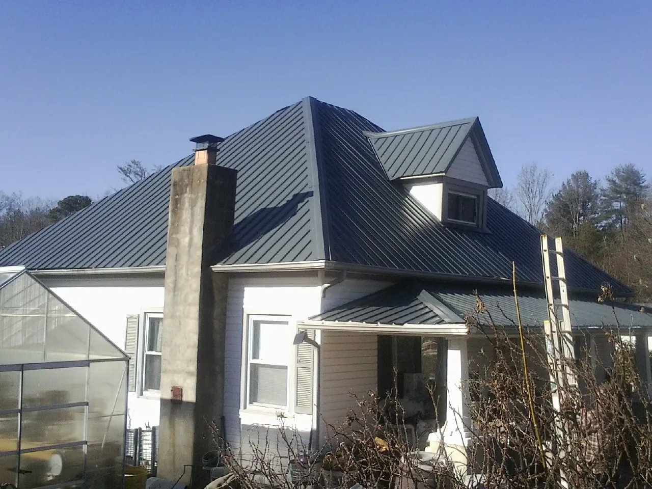 Dark blue standing seam metal roof on a white farmhouse with dormer — Slate & Tile Roof Repair by Roofing Brothers in Sparks