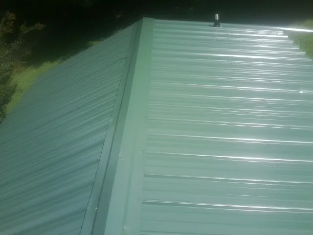 New green metal panels meeting at the ridge of a roof — Flat Roof Repair work by our crew in Sparks